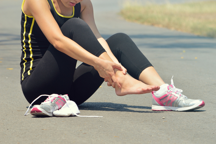 Foot Pain: Young woman suffering from an ankle injury while exercising and running